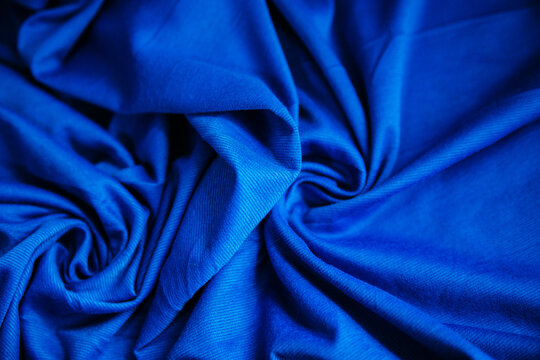 Blue wrinkled draped fabric. Sewing material is on the table.