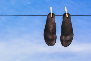 Black insoles drying on laundry or clothes line - obrazy, fototapety, plakaty