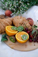 picnic in summer with snacks, fresh fruits and flowers. croissants, kiwi, orange, cherry. background top view mockup,a place for text