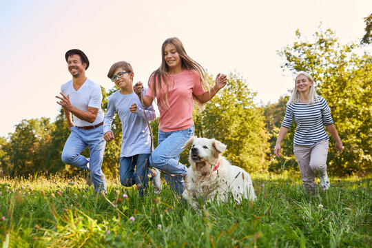 Familie und Kinder mit Hund haben Spaß beim Laufen