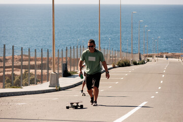 A man playing figure skating on a rural road in the sun on a bright day, Play surf skate near coast