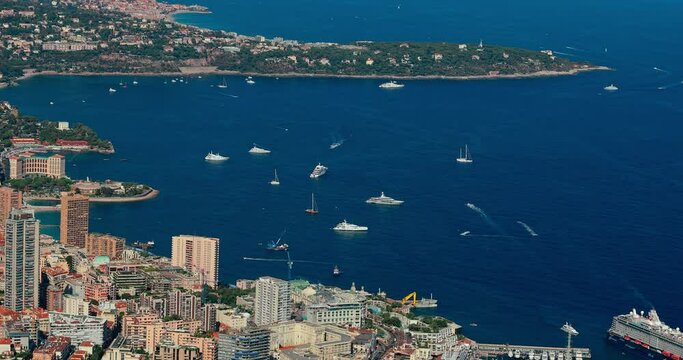 Aerial view of principality of Monaco at sunset, Monte-Carlo, luxury buildings, soccer stadium, view of city life from La Turbie mountain, a lot of mega yachts and boats, water horizon 