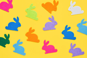 Easter concept. Multi-colored figurines of Easter bunnies on a yellow background. Top view