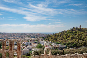 Fototapeta na wymiar View of the ancient building Odeon of Herodes and the houses of the city of Athens, Greece.