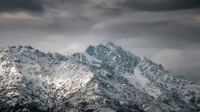 Time lapse of dark clouds over a snow capped Monte Grosso in the Balagne region of Corsica