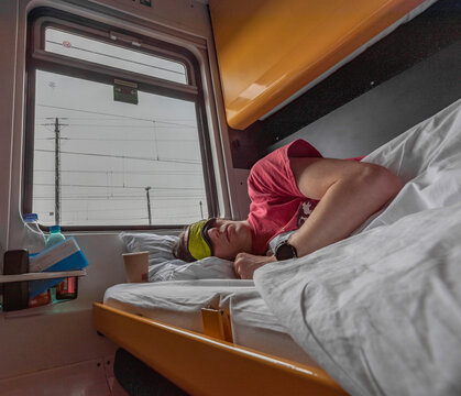 Blue and yellow interior of sleeping coach with sleeping man
