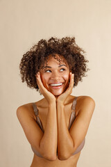 Happy multiracial female posing at camera over beige background
