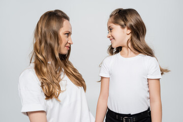 cheerful girl looking at mother isolated on grey.