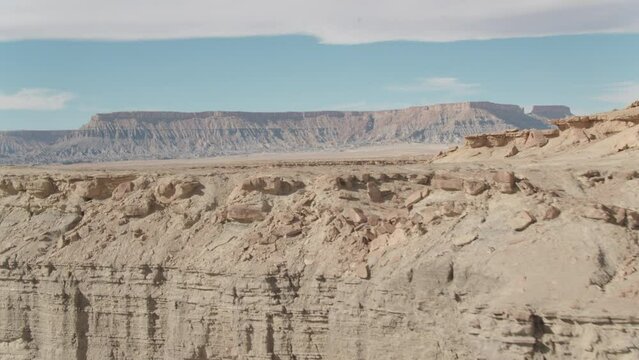 Utah desert aerial ascending up and revealing past brown mesa to horizon