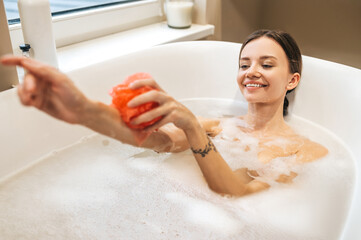 Naklejka premium Cheerful lady washing herself with a nylon loofah