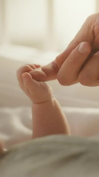 Vertical Format Video of a Close Up with Newborn Baby Hand Holding Mother's Finger while Lying in Child's Crib at Home. Concept of Childhood, New Llife, Parenthood.