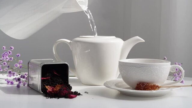 Pour hot water into a white teapot. Table setting for receiving guests. Brew black tea. HLS. Breakfast without coffee