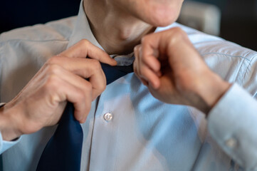 A businessman in a blue shirt untieing his tie