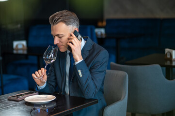 An elegant man trying white wine and looking contented