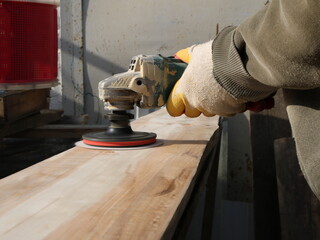 processing a grinder with an emery nozzle of a board in a carpenter's workshop, smoothing and...