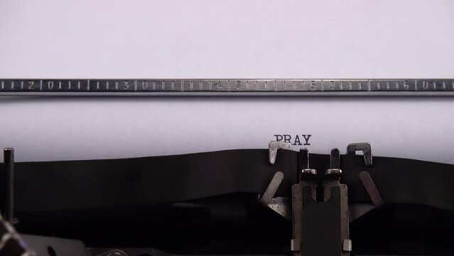Typing phrase PRAY for UKRAINE on retro typewriter.