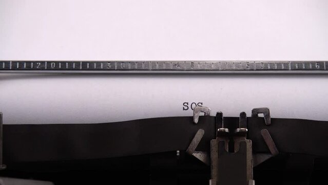Typing phrase SOS HELP Ukraine on retro typewriter.