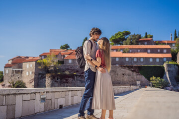 Man and woman tourists on background of beautiful view of the island of St. Stephen, Sveti Stefan on the Budva Riviera, Budva, Montenegro. Travel to Montenegro concept