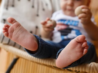 portrait a one year children foot on background. cute baby boy legs close up portrait. littte child without  socks and shoes sitting on chair. bare feet little boy