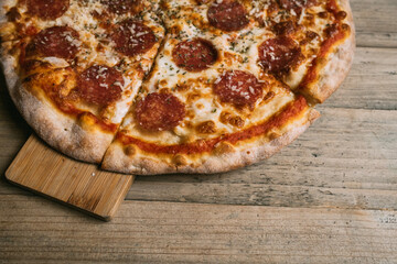 Delicious hot meat pizza with prosciutto and salami on a wooden table. High quality photo
