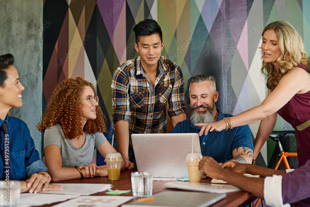Poster Compiling their best ideas together. Shot of a group of designers working together on a laptop in an office.