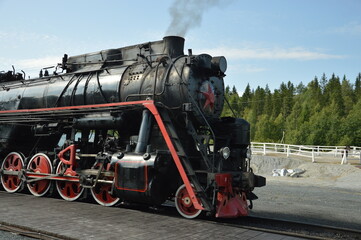 retro train in karelia, russia. steam train on move in forest. old authentic train on go, summer. black and red train