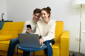 Portrait of a smiling young couple using laptop at home indoor