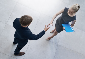 Merging skills to achieve success. High angle shot of two unrecognizable businesspeople shaking hands in a corporate office.