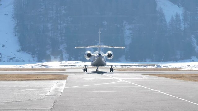 Rear Shot Private Jet Taxiing to Runway for Departure from Winter Mountains.