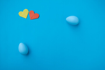 Colorful egg and paper hearts on blue background.. Easter egg. Copy space