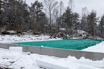 Foundations for a residential house in snowy winter scene. Blue and green covering.