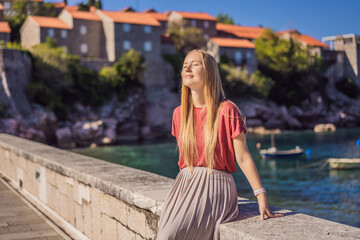 Fototapeta premium Woman tourist on background of beautiful view of the island of St. Stephen, Sveti Stefan on the Budva Riviera, Budva, Montenegro. Travel to Montenegro concept