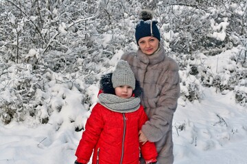Fototapeta na wymiar Walk mother and daughter girls in a beautiful, fabulous snowy forest.