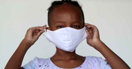 Little boy putting covid-19 face mask, child puts surgical mask, mixed race african ethnicity