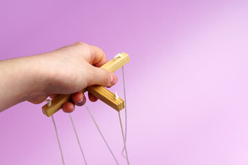 Hand holds a D-pad with ropes to control the puppet puppet