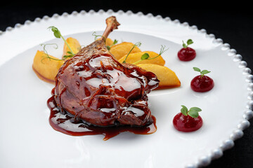 Duck leg with pear in caramel, on a white plate