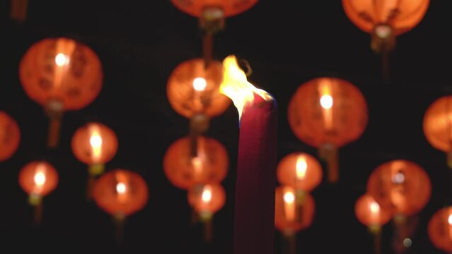 Burning of red large incense joss stick with the background of illuminated red chinese lantern