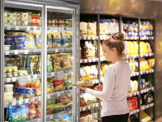 Woman choosing frozen food from a supermarket freezer.choosing a dairy products at supermarket.