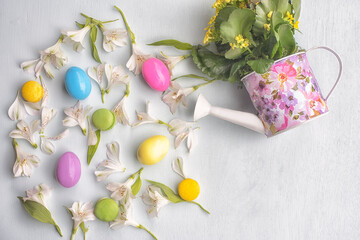 Spring Easter still life. Delicate flowers and colored eggs - a symbol of Easter on a light background. View from above.