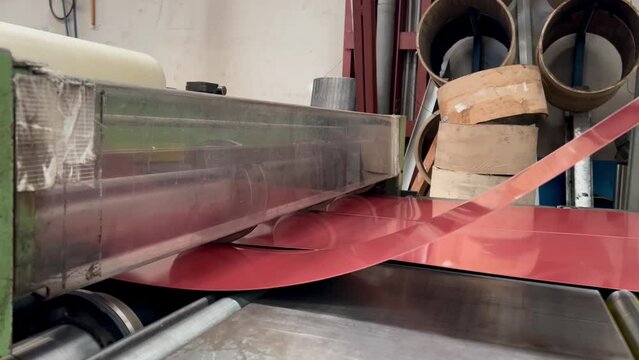 4K video of a metal company's cutting machine at work cutting a red galvanized pre-painted sheet metal. metalworking industry