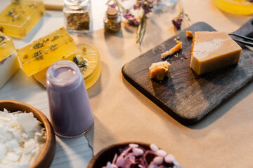 Obraz na płótnie Canvas Handmade soap on wooden cutting board near dry flowers on blurred background.