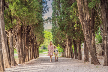 Mom and son tourists walking together in Montenegro. Panoramic summer landscape of the beautiful green Royal park Milocer on the shore of the the Adriatic Sea, Montenegro