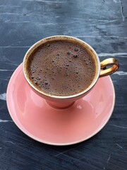 Turkish coffee in pink ceramic cup on a marble table