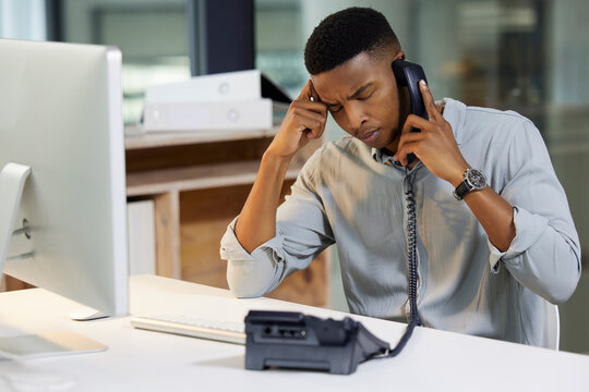 Delivering bad news is a tough call to make. Shot of a young man using a phone and looking stressed in a modern office.