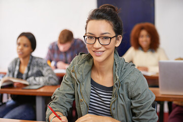 A solid education for a promising future. Portrait shot of a happy female student sitting at her desk.