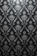 Vintage graphic or texture in steampunk style, light grey vines and leaves on a black background. Vertical photo.