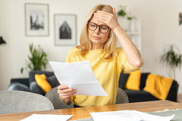 Confident elderly businesswoman is doing paperwork while sitting at the table at the office....