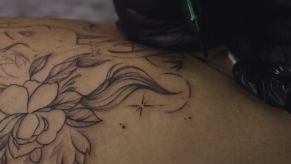 Professional female tattoo artist makes a tattoo in the studio, close-up. Dark 4k video