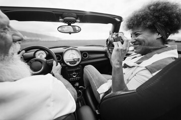 Happy senior couple having fun in convertible car during summer vacation - Focus on woman hand...