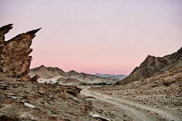 Fototapeta na wymiar Through an otherworldly landscape. Shot of a dirt road running through rugged terrain.